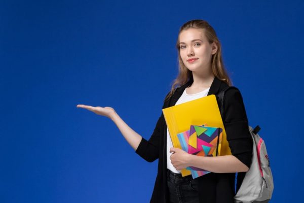 front-view-female-student-white-shirt-black-jacket-wearing-backpack-holding-files-with-copybooks-blue-wall-college-university-lessons-min