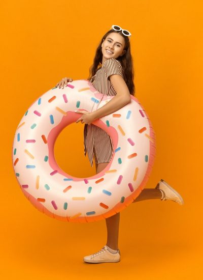 vertical-image-cheerful-pretty-girl-going-beach-carrying-rubber-circle-min